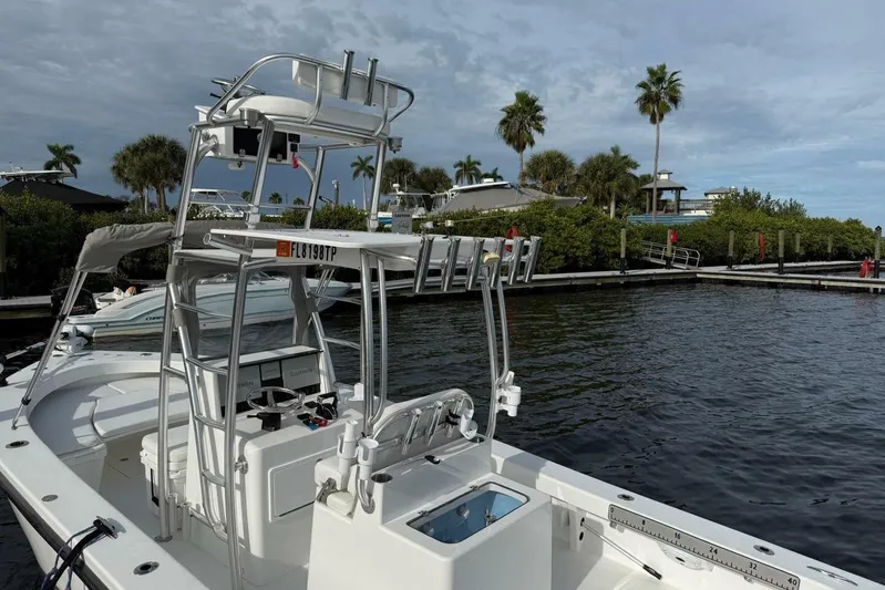  Yacht Photos Pics 2023 T Craft 27 boat docked by palm trees under cloudy sky.