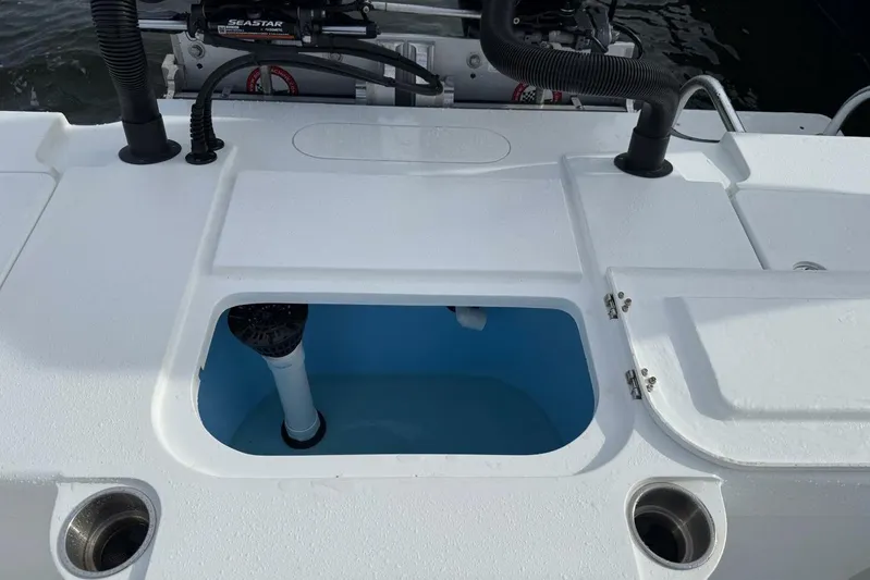  Yacht Photos Pics 2023 T Craft 27 boat deck with open storage compartment and visible plumbing.