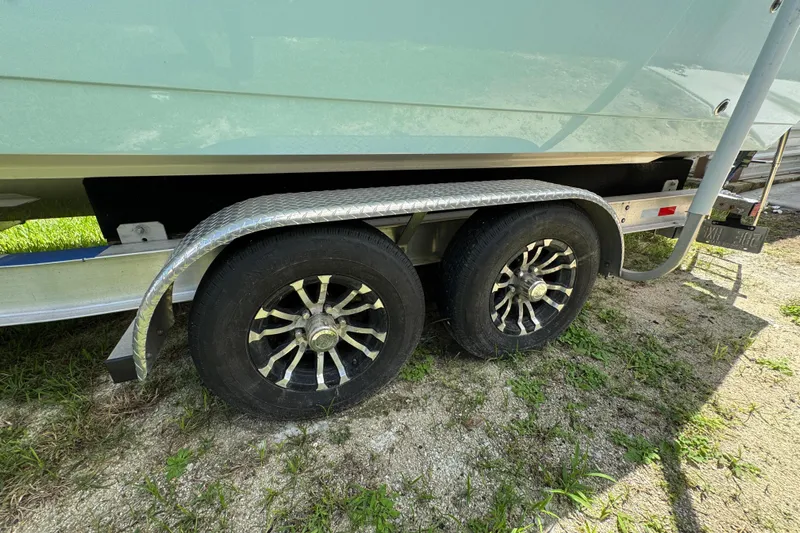  Yacht Photos Pics Trailer wheels of a 2024 Cobia 280 Center Console boat on grass.