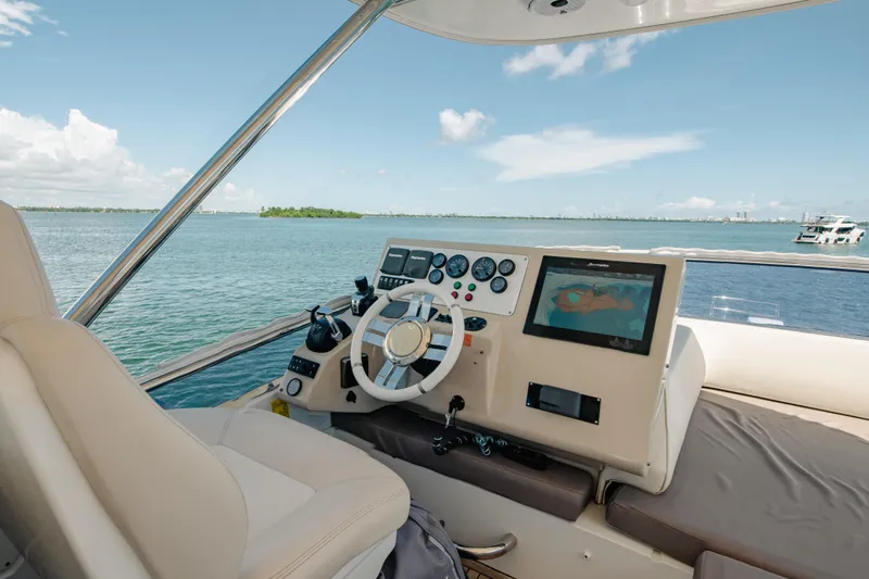 Prime Time II Yacht Photos Pics 2016 Azimut 64 Flybridge helm with navigation display, overlooking serene waters and distant shoreline.
