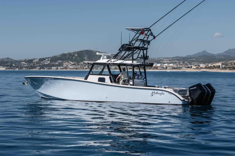  Yacht Photos Pics 2025 Yellowfin 42 Offshore boat on calm water with scenic coastal backdrop.