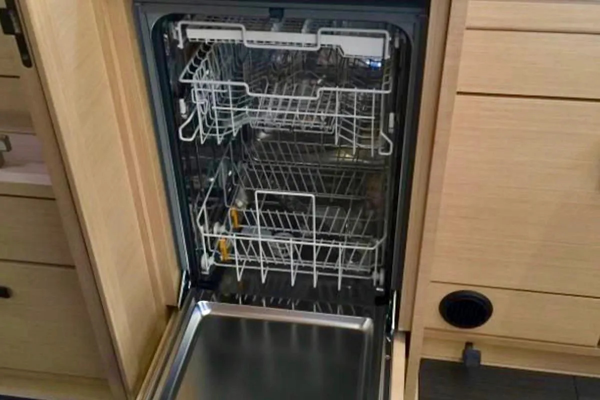 Open dishwasher in Jeanneau 54 yacht kitchen, showcasing interior racks and modern design.