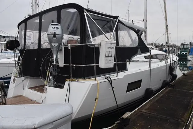 2016 Jeanneau 54 yacht docked, featuring a covered cockpit and outboard motor.