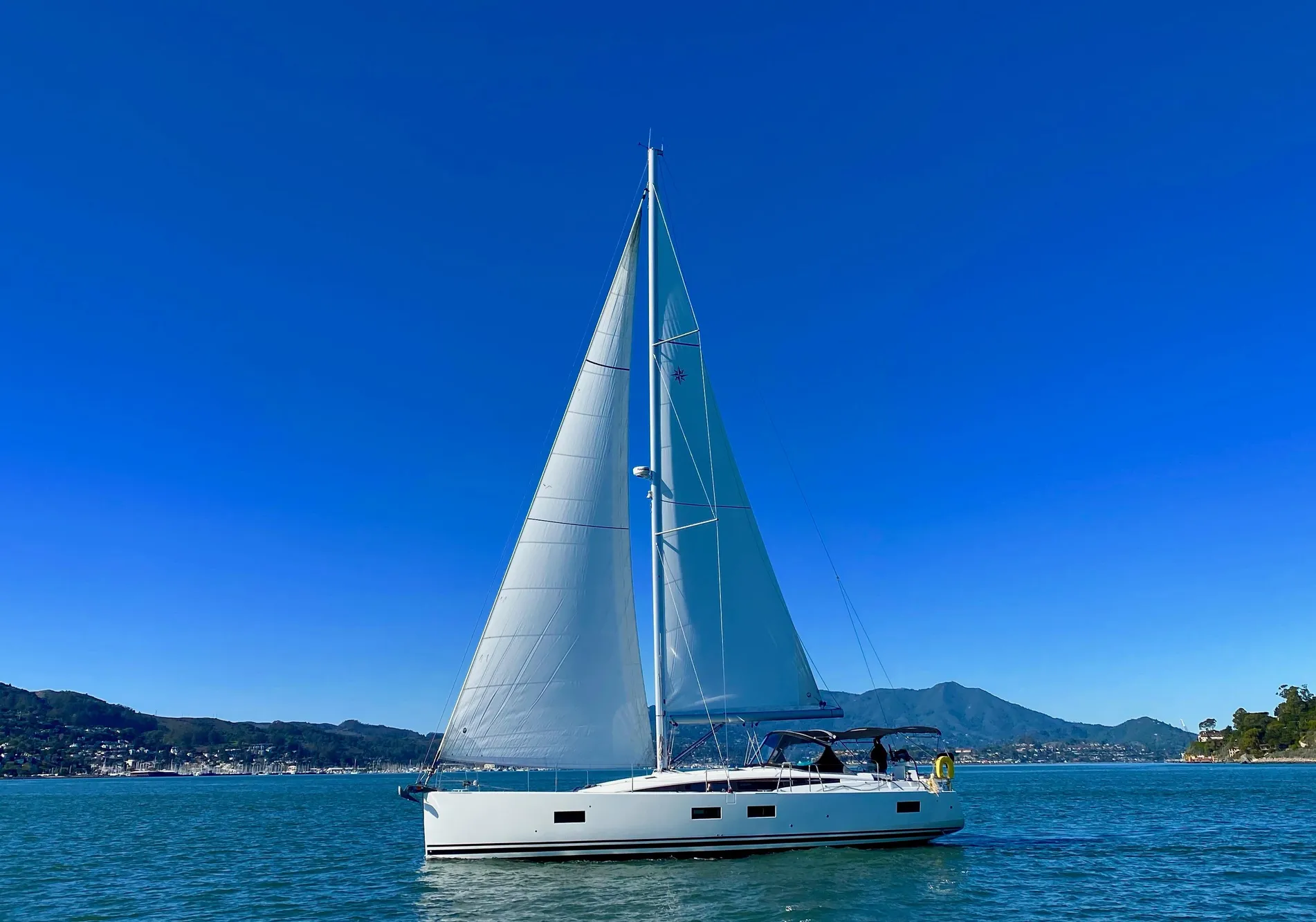 Jeanneau 54 sailboat from 2016 on calm waters under a clear blue sky.
