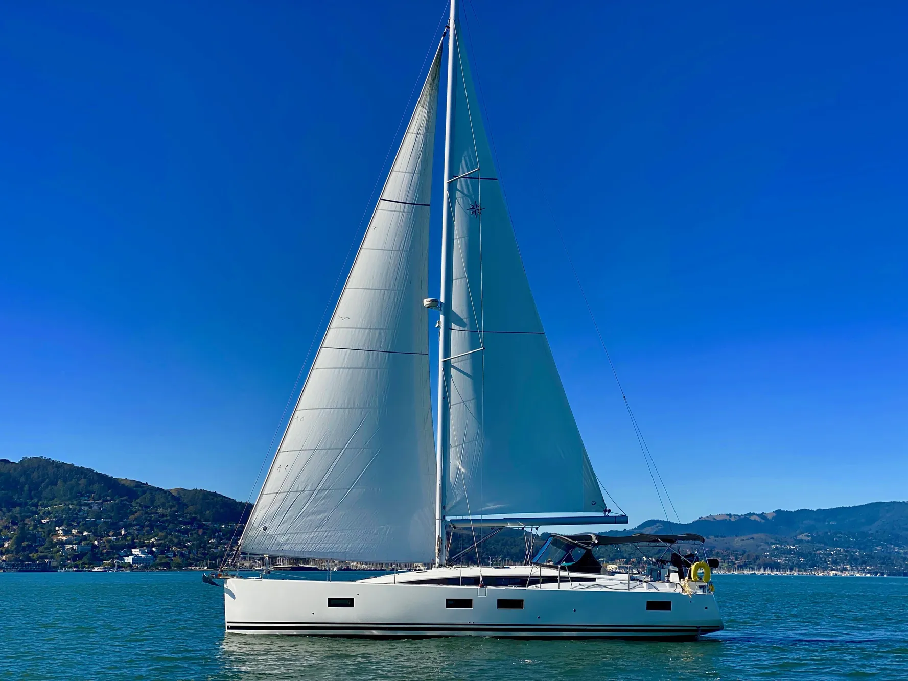 2016 Jeanneau 54 sailboat on calm water with clear blue sky.