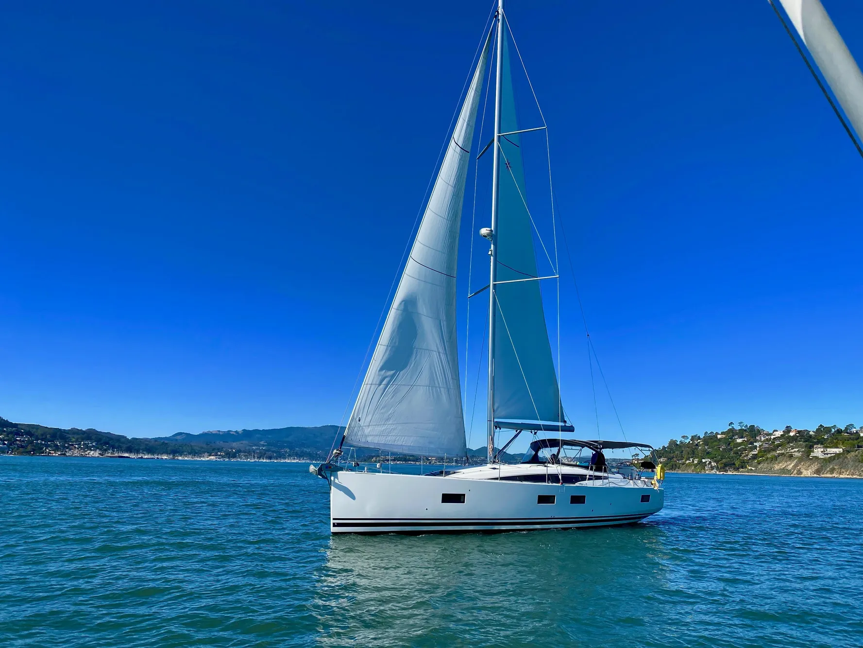 2016 Jeanneau 54 sailboat on calm blue waters under clear skies.