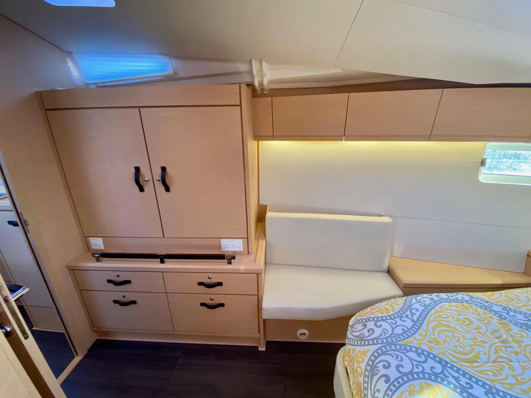 Interior of 2016 Jeanneau 54 yacht cabin with wood cabinetry and cozy seating area.