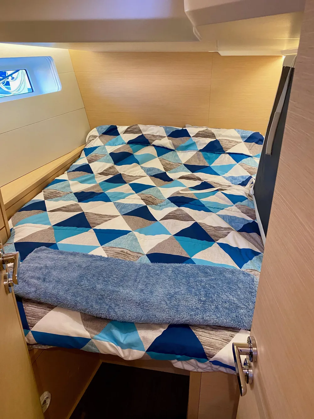 Cozy cabin bed in 2016 Jeanneau 54 yacht with geometric-patterned bedding.