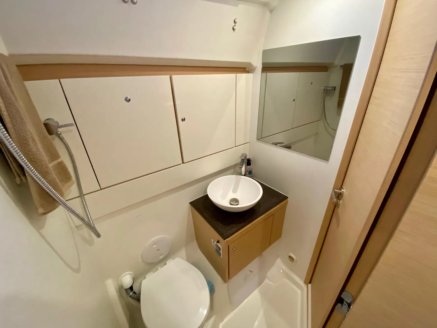 Compact bathroom in a 2016 Jeanneau 54 yacht with modern fixtures and storage.
