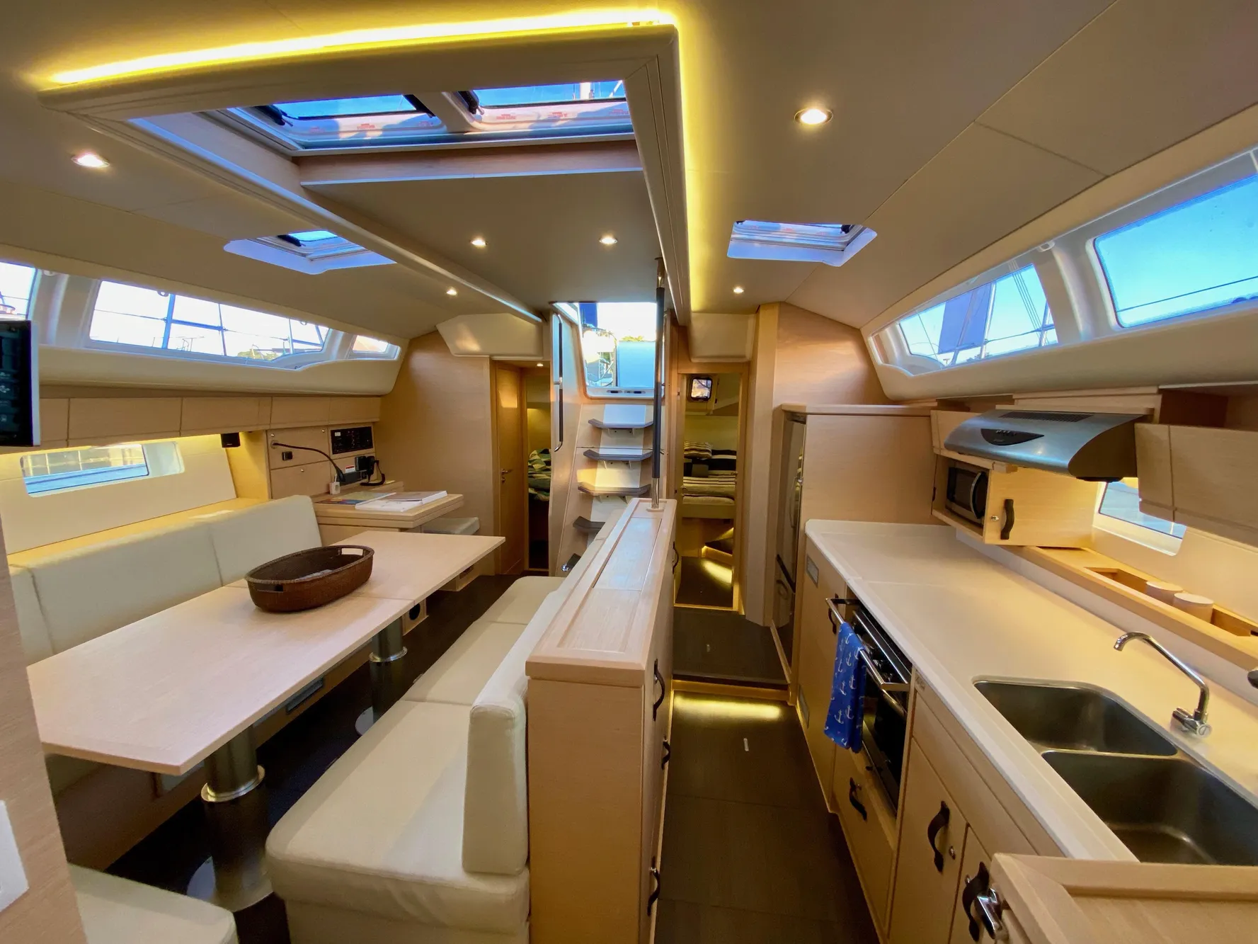 Luxurious interior of a 2016 Jeanneau 54 yacht, featuring modern kitchen and dining area.