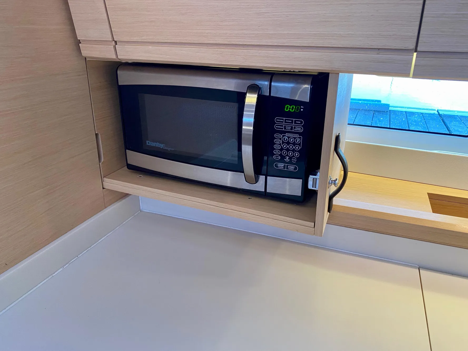 Microwave in Jeanneau 54 yacht kitchen, 2016 model, with light wood cabinetry.