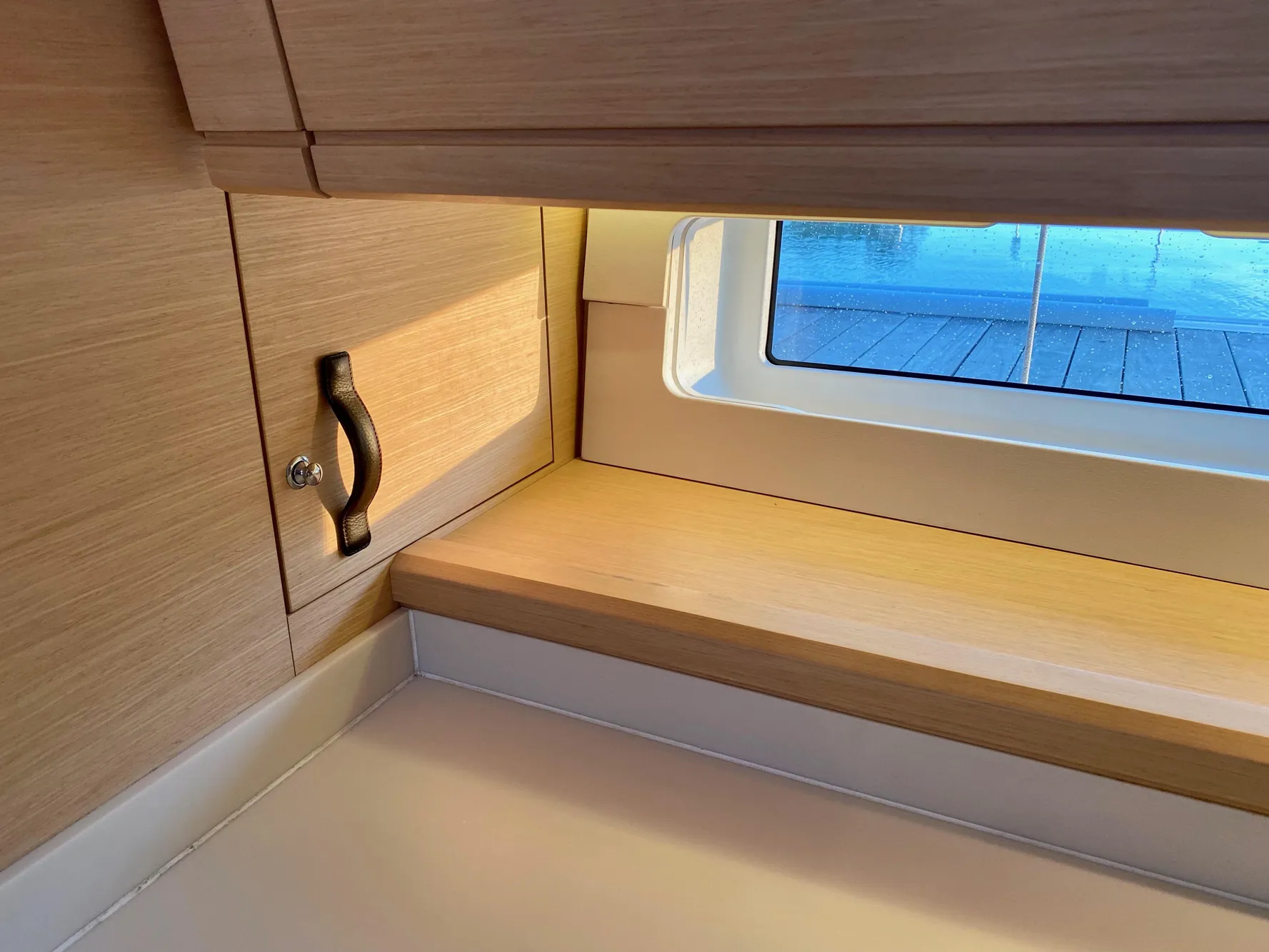 Interior of a 2016 Jeanneau 54 yacht, featuring a wooden cabinet and window.