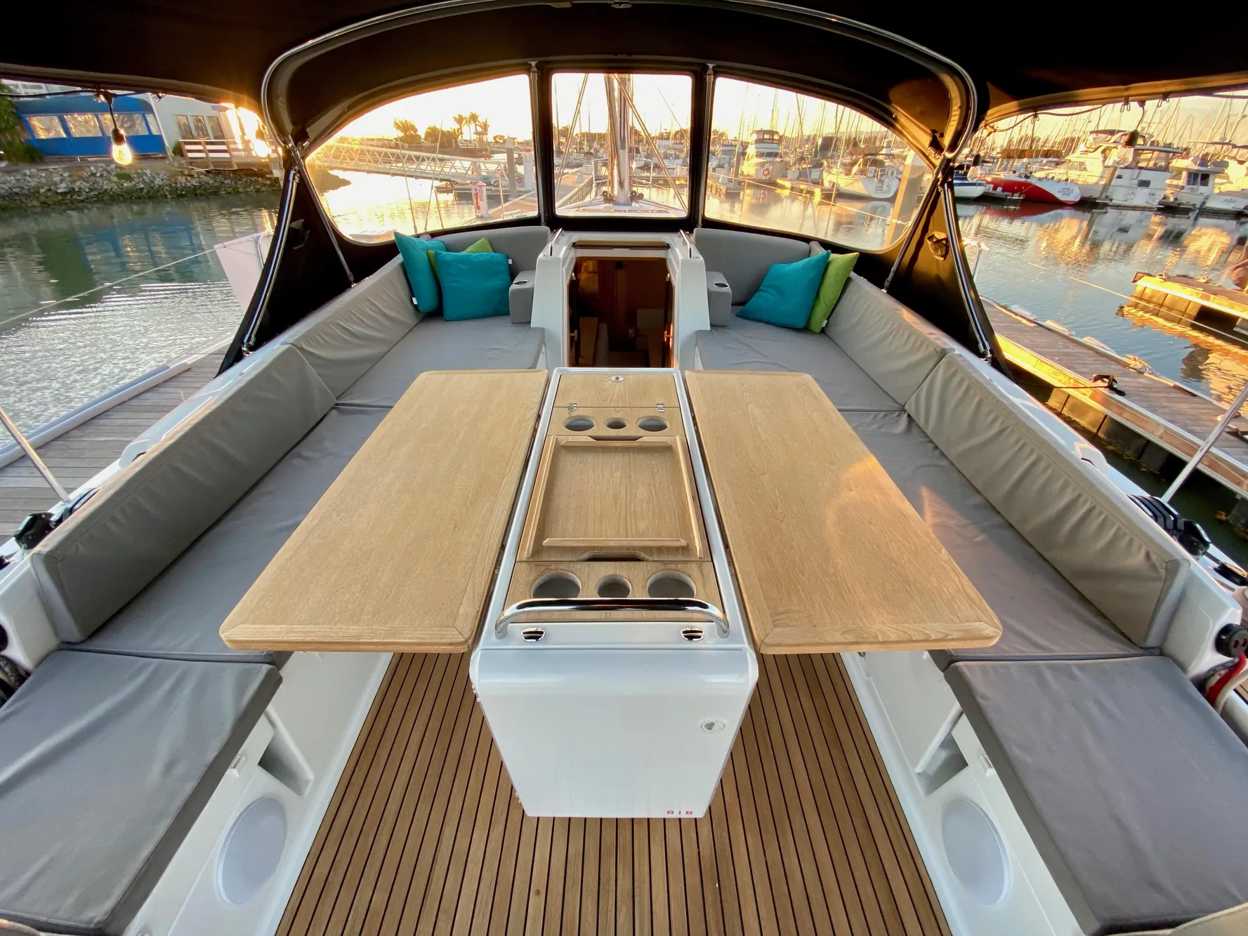 Luxurious Jeanneau 54 yacht cockpit with cushioned seating and wooden table, 2016 model.