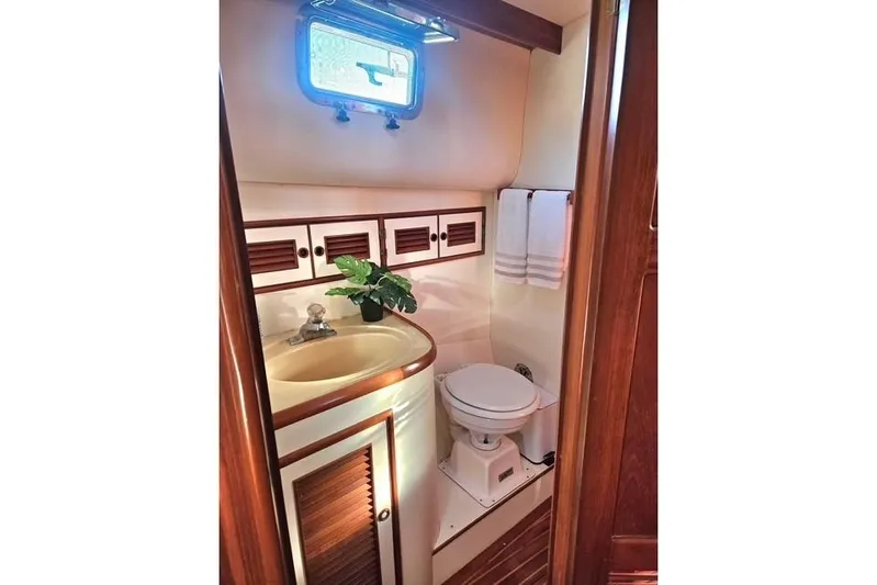 Southern Flite Yacht Photos Pics 1990 Offshore Yachts Trawler bathroom with sink, toilet, and wooden cabinetry.