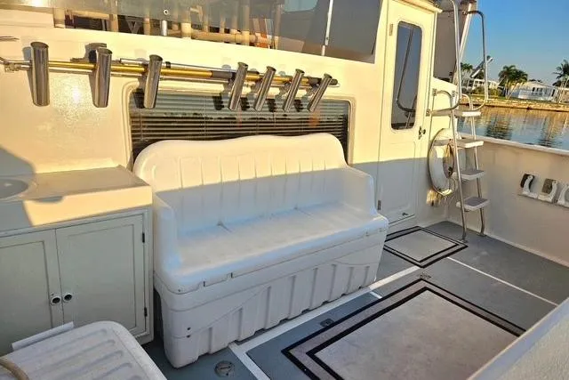 Southern Flite Yacht Photos Pics 1990 Offshore Yachts Trawler deck with seating, rod holders, and ladder, docked by water.