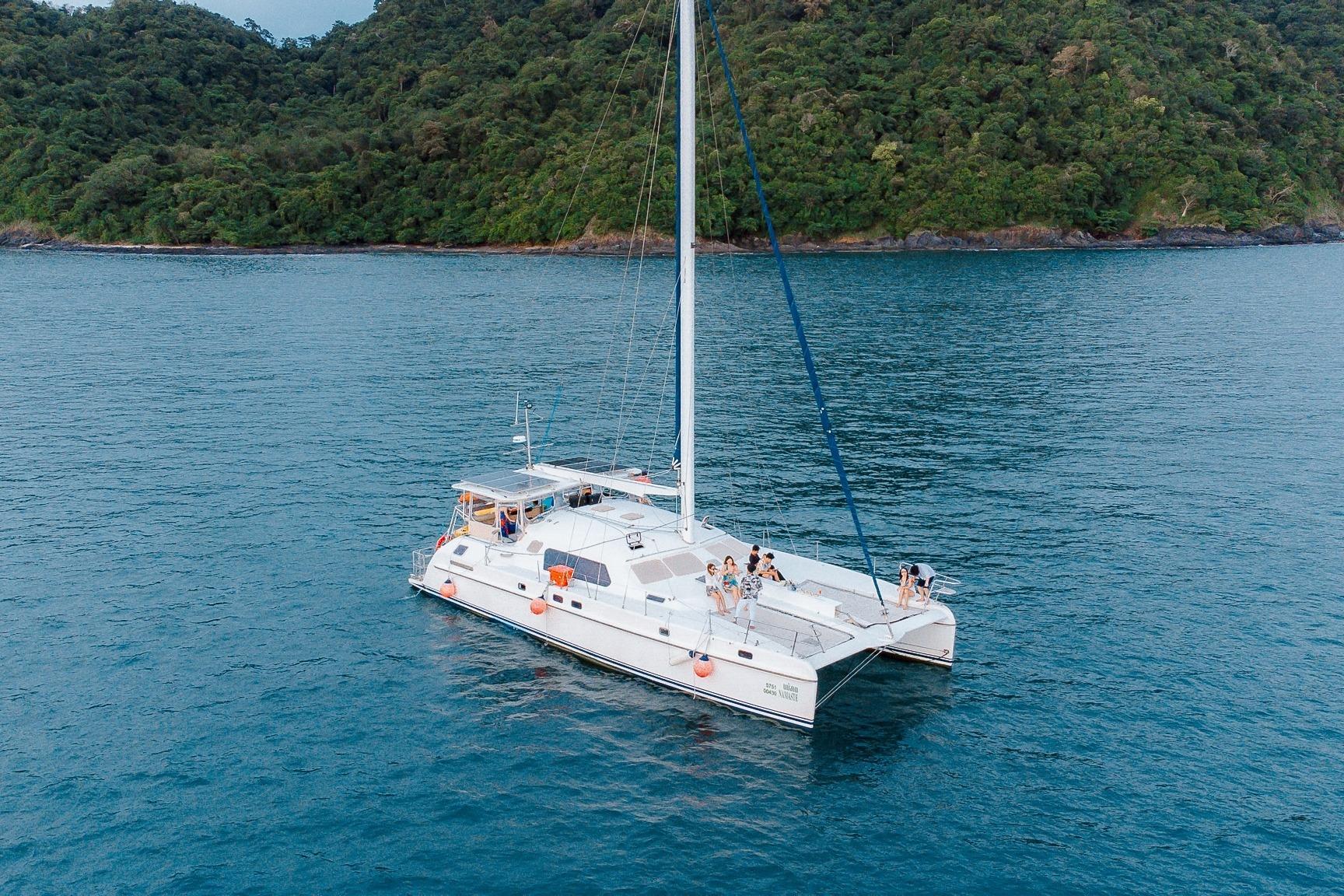 Sailboat IMP 55, 2001 model, cruising near lush green coastline.
