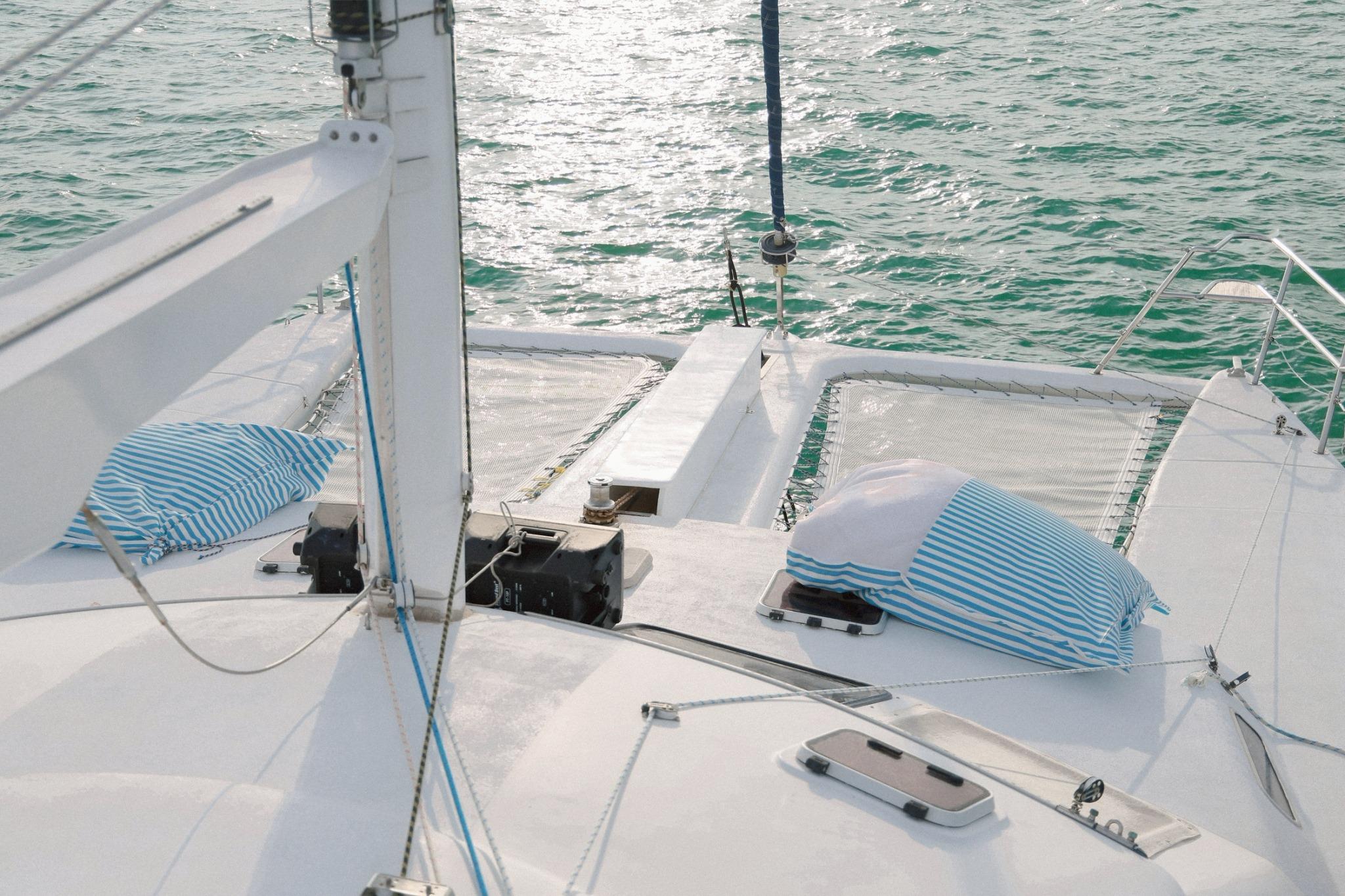 Sailing catamaran deck with striped cushions, IMP 55 model, 2001, on calm sea.
