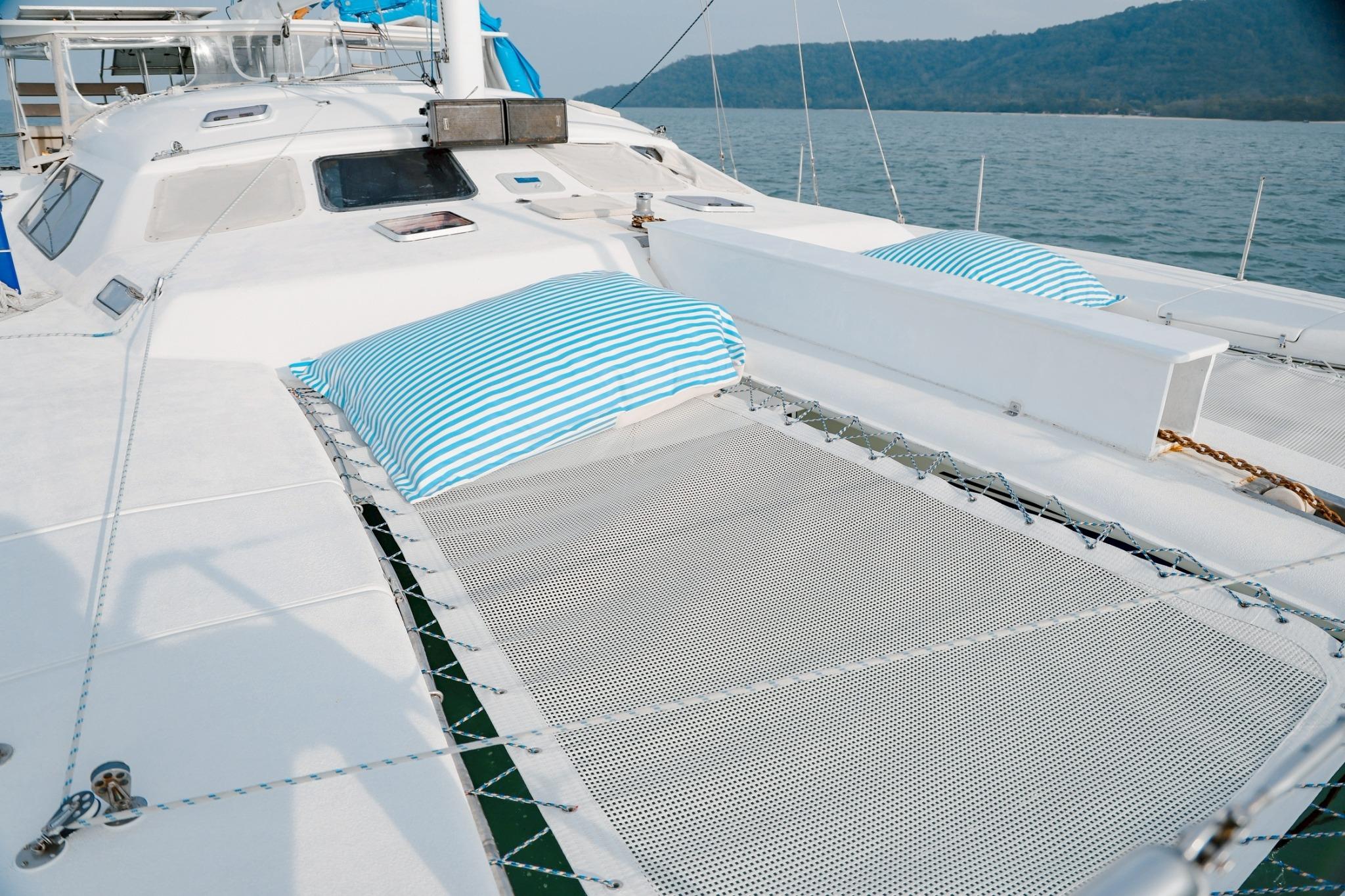 Deck of IMP 55 yacht with striped cushions, featuring a netted lounging area.