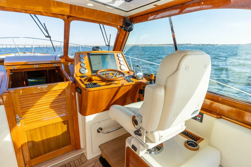 Upshort Yacht Photos Pics Helm of 2010 Hinckley Talaria 44 MKII Express yacht with wooden dashboard and white captain's chair.