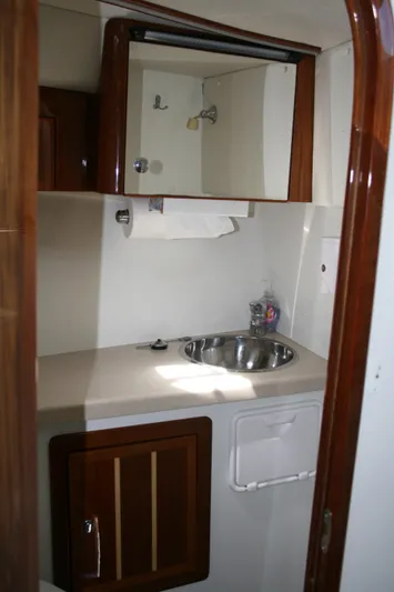 Gypsy Spirit Yacht Photos Pics 2011 Ocean Sport Roamer 30' bathroom with sink, mirror, and wooden cabinetry.