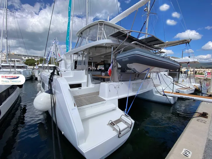  Yacht Photos Pics 2025 Lagoon 46 catamaran docked at marina under blue sky.