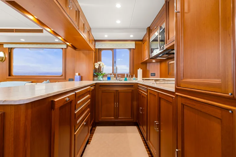  Yacht Photos Pics Luxurious kitchen interior of 2023 Fleming 65 yacht with wooden cabinetry and ocean view.
