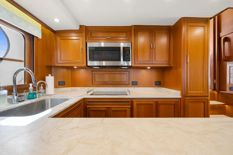  Yacht Photos Pics Luxurious kitchen in 2023 Fleming 65 yacht with wood cabinetry and modern appliances.