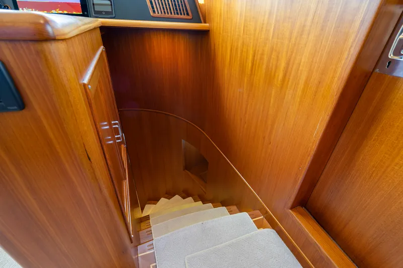  Yacht Photos Pics Wooden staircase inside 2023 Fleming 65 yacht, featuring elegant design and carpeted steps.