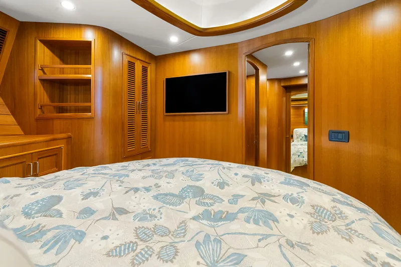  Yacht Photos Pics Luxurious cabin interior of 2023 Fleming 65 yacht with wood paneling and floral bedding.