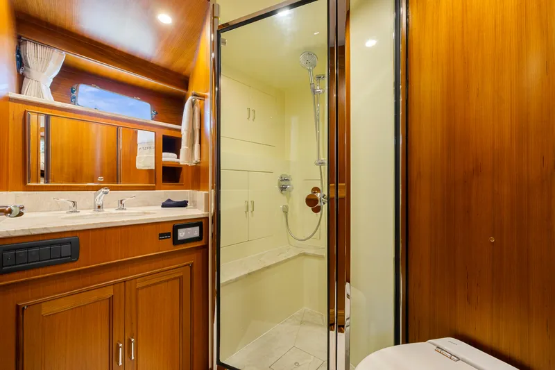  Yacht Photos Pics Luxurious bathroom in 2023 Fleming 65 yacht with wooden cabinetry and modern shower.