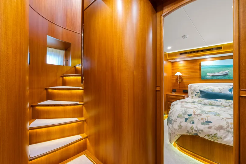  Yacht Photos Pics Luxurious interior of 2023 Fleming 65 yacht with wooden staircase and cozy bedroom.