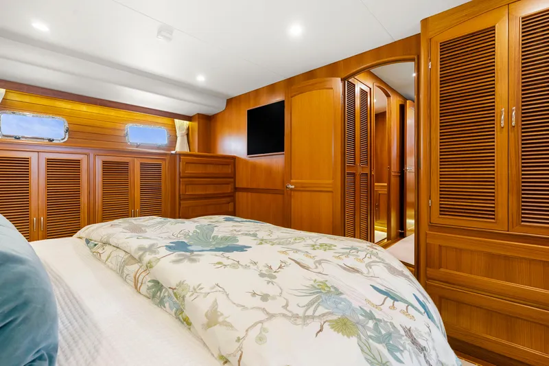  Yacht Photos Pics Luxurious cabin interior of 2023 Fleming 65 yacht with wooden furnishings and floral bedding.