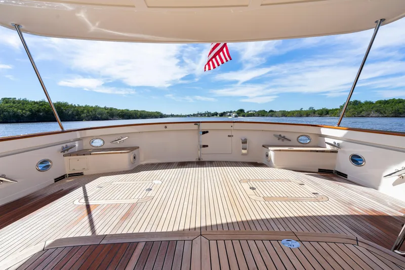  Yacht Photos Pics Spacious deck of 2023 Fleming 65 yacht with American flag, overlooking serene waters.