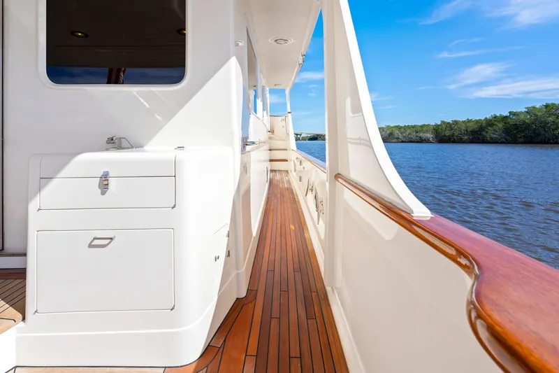  Yacht Photos Pics Side deck of 2023 Fleming 65 yacht with wooden flooring, overlooking serene water and blue sky.