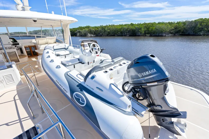  Yacht Photos Pics 2023 Fleming 65 yacht with Yamaha motorboat on deck, near lush shoreline.