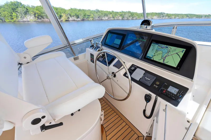  Yacht Photos Pics 2023 Fleming 65 yacht helm with navigation screens and steering wheel on a serene waterway.