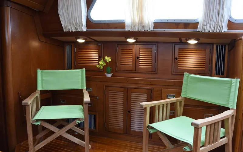 Wanderer Yacht Photos Pics Interior of 1982 Hinckley Sou'wester 59 yacht with wooden cabinets and green chairs.
