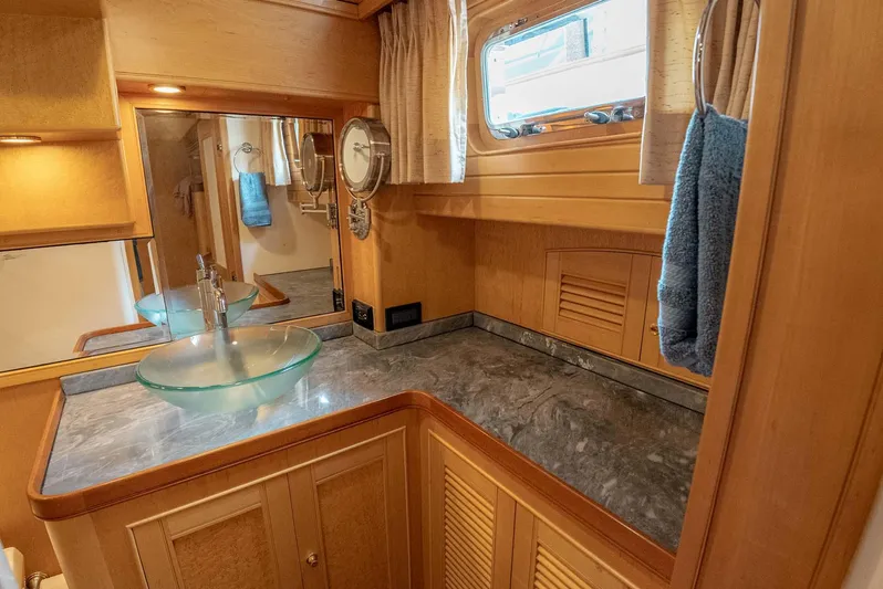 Someday Came Yacht Photos Pics Luxurious bathroom in 2006 Marlow 72E LRC yacht with glass sink and wooden cabinetry.
