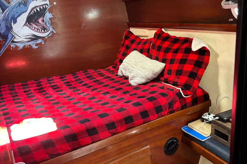 Thalassa Yacht Photos Pics Cozy cabin in 2005 Fountaine Pajot Bahia 46 with red plaid bedding and shark wall art.