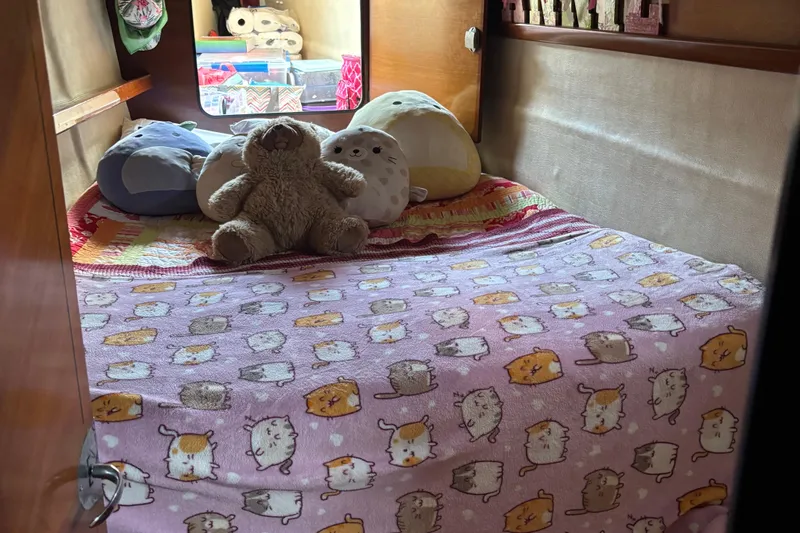 Thalassa Yacht Photos Pics Cozy cabin bed with plush toys and cat-themed blanket on 2005 Fountaine Pajot Bahia 46.