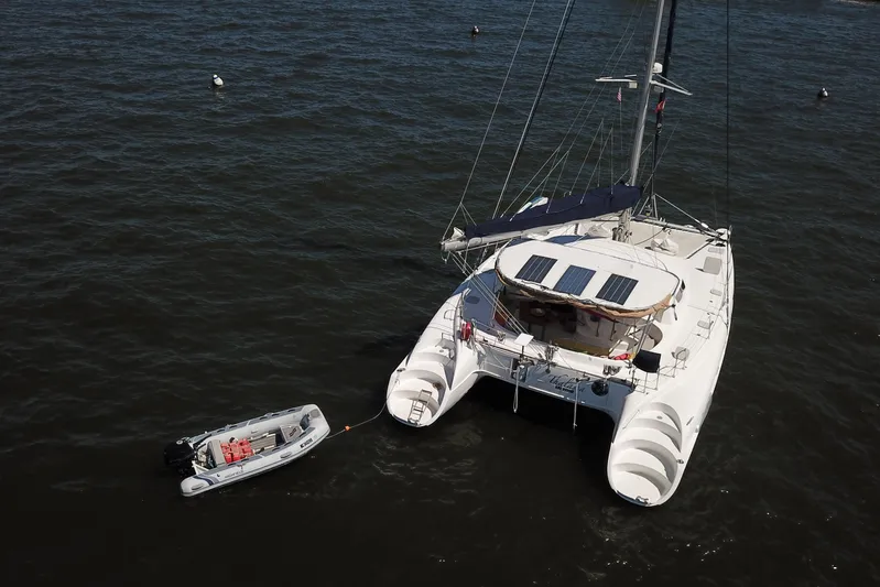 Thalassa Yacht Photos Pics 2005 Fountaine Pajot Bahia 46 catamaran with dinghy on calm water.