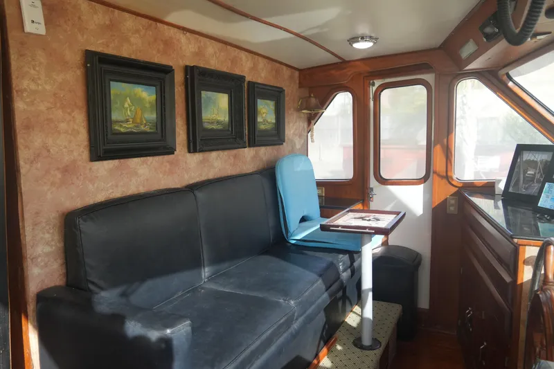 God's Favor Yacht Photos Pics Interior of 1986 DeFever 53 POC yacht with black sofa and nautical paintings.
