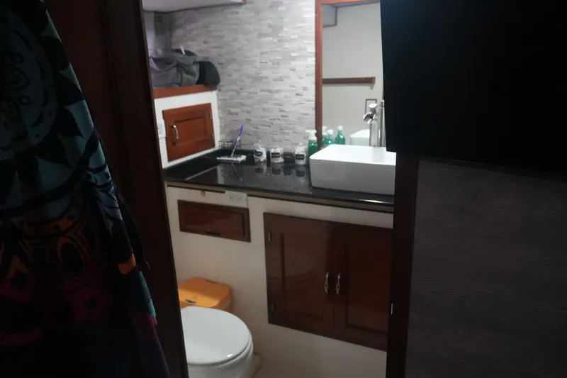 God's Favor Yacht Photos Pics 1986 DeFever 53 POC yacht bathroom with modern sink, wooden cabinets, and tiled backsplash.