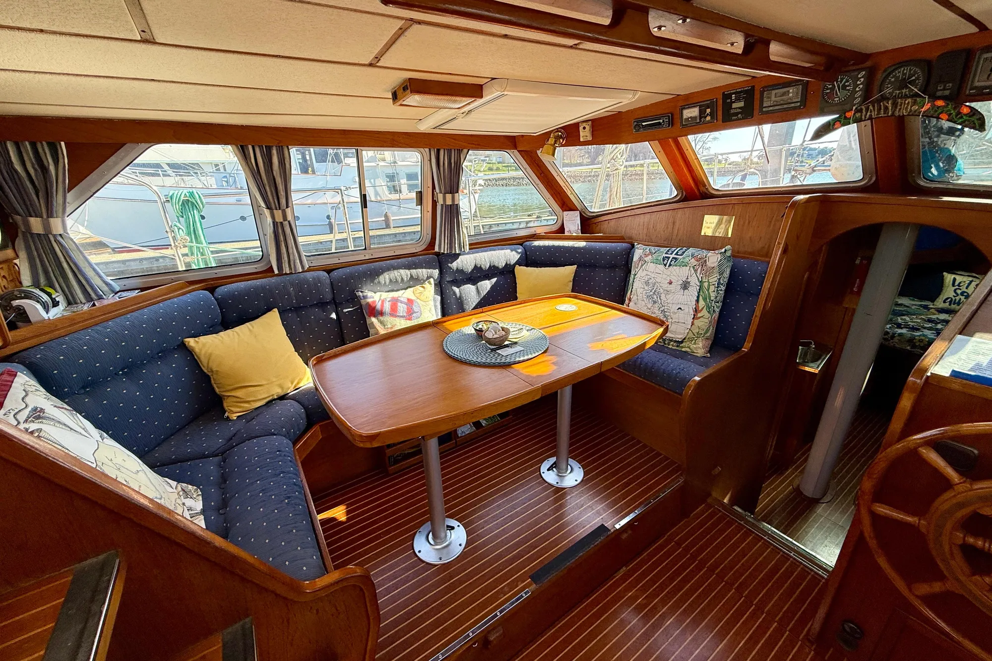 1986 Nauticat 43 yacht interior with cozy seating and wooden dining table.