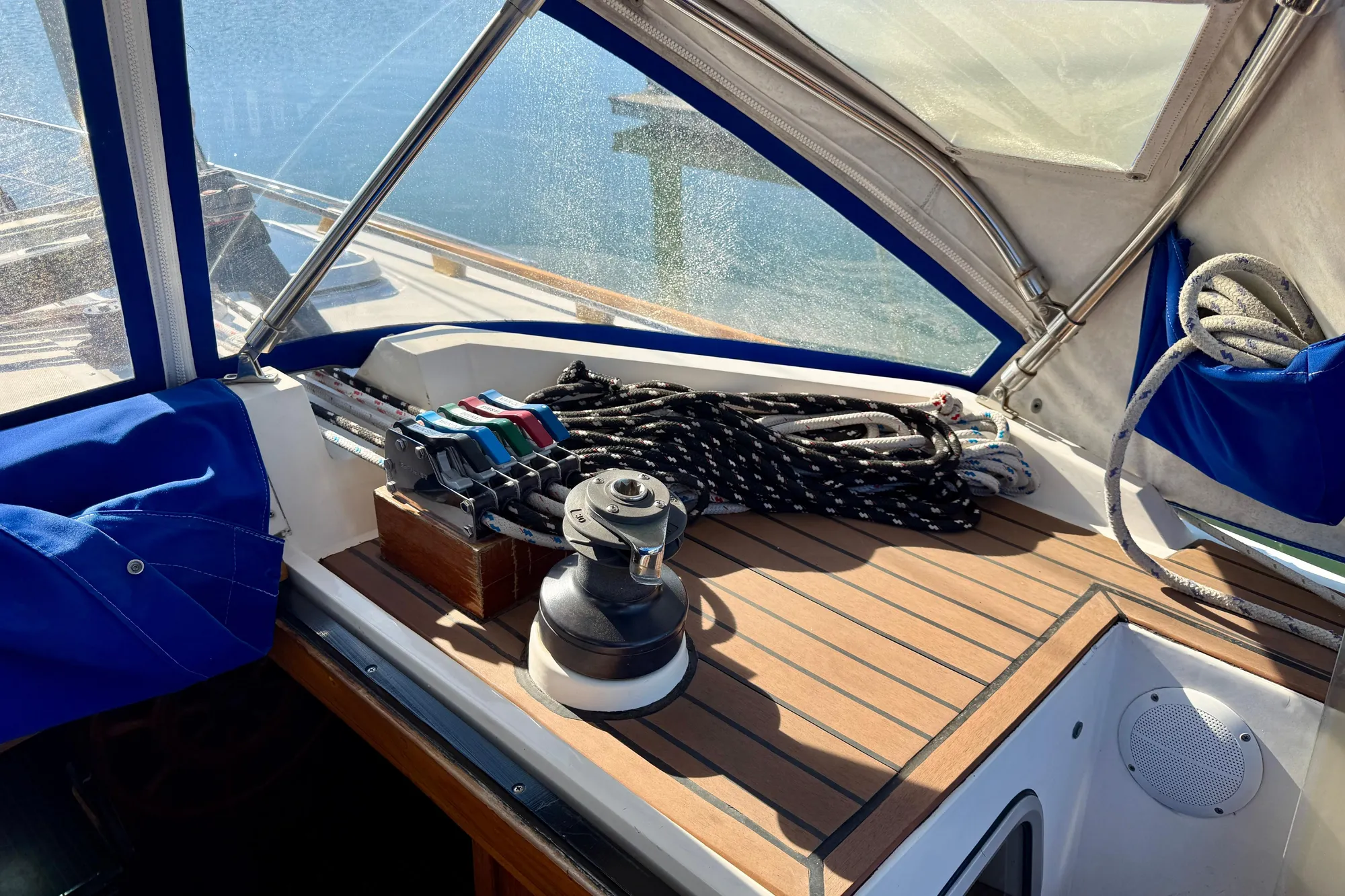 Cockpit of 1986 Nauticat 43 sailboat with winch and line clutches, under hard dodger.