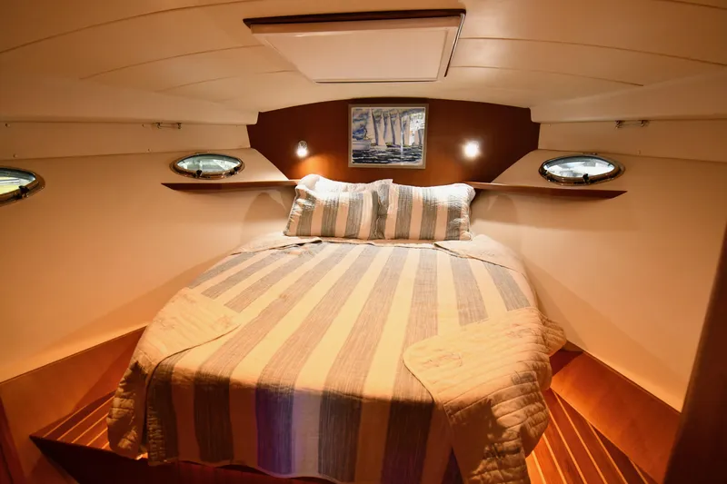 Promesa Yacht Photos Pics Cozy cabin interior of 2021 Hylas M44 yacht with striped bedding and porthole windows.