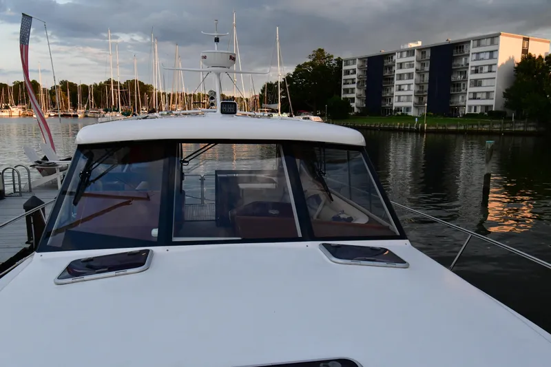 Promesa Yacht Photos Pics 2021 Hylas M44 yacht docked in a marina with buildings and sailboats in the background.
