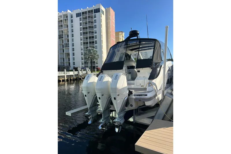 Jet Privé Yacht Photos Pics 2021 Searay 370ob boat docked with triple outboard engines, near waterfront buildings.