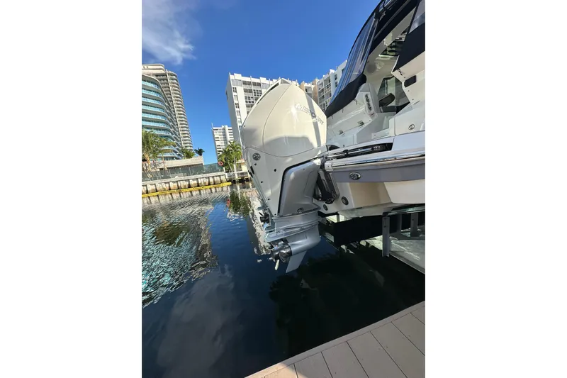 Jet Privé Yacht Photos Pics 2021 Searay 370ob boat docked near modern buildings, reflecting on calm water.