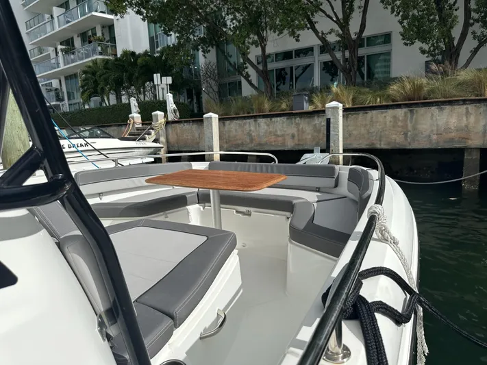 Jebang Yacht Photos Pics 2023 Jeanneau Leader 9.0 CC boat with spacious seating and wooden table docked by waterfront.